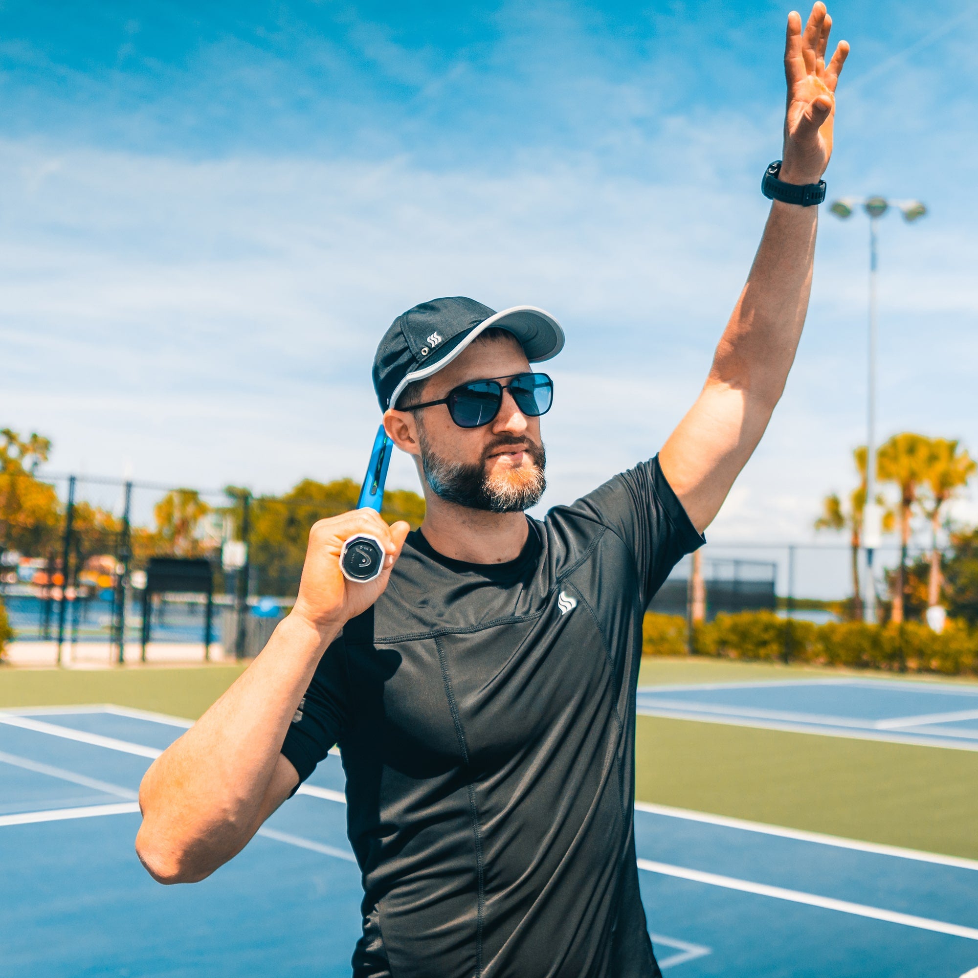 Man playing tennis in a black dry fit hat