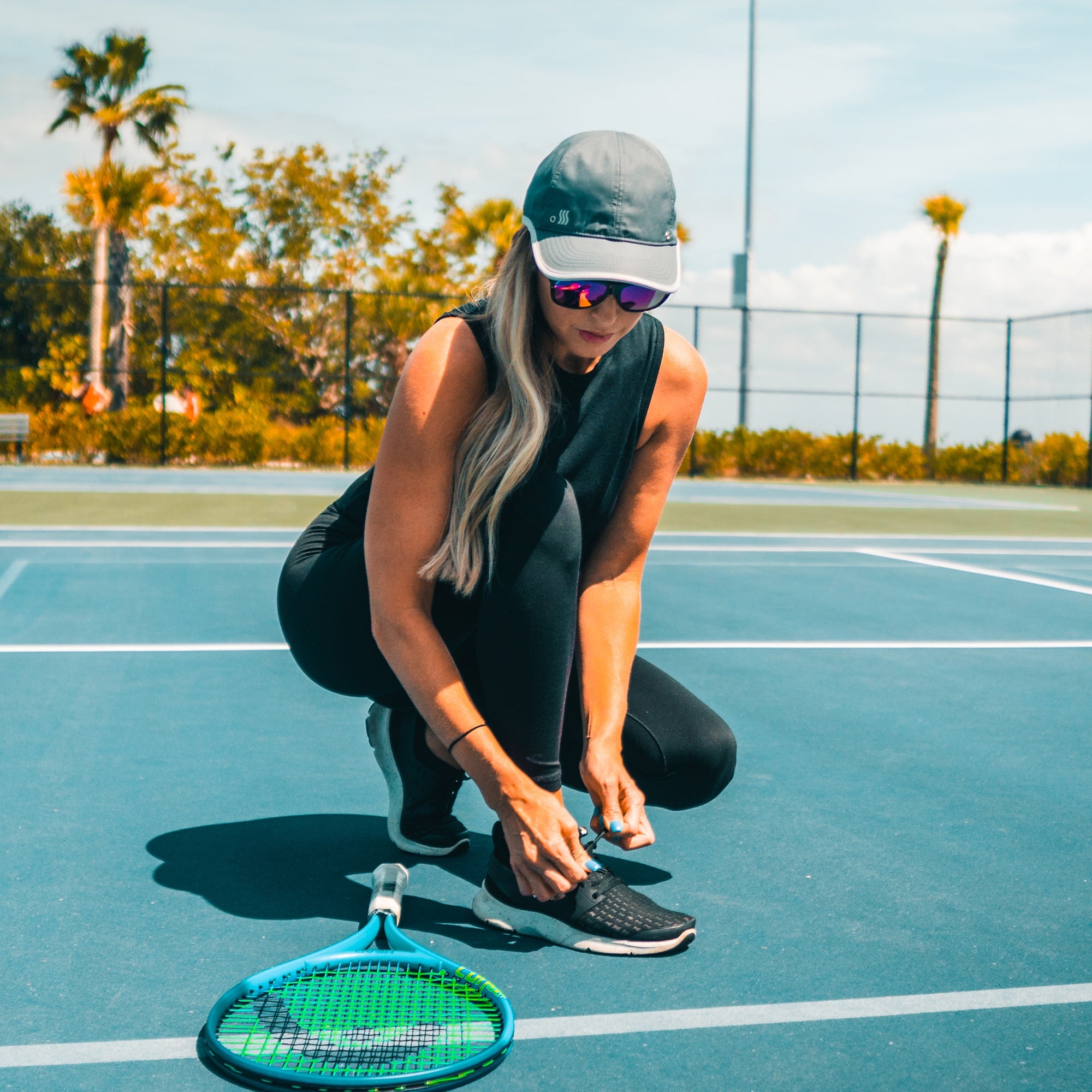 Women playing tennis while wearing a moisture wicking hat